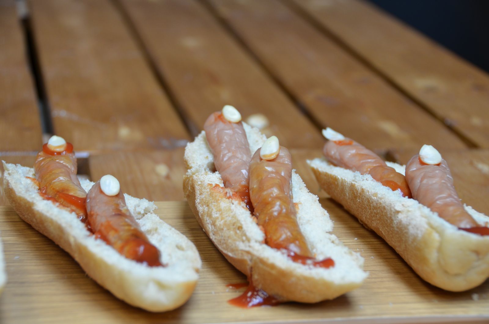 Horizontally Cut Bread rolls with Sausages place upon each slice. Made to look like Witches Fingers with an Almond flake as the Fingernail and Tomato Ketchup as blood.